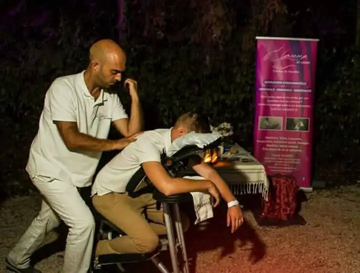 Massage assis en soirée, devant le kakémono AMMA by Cédric